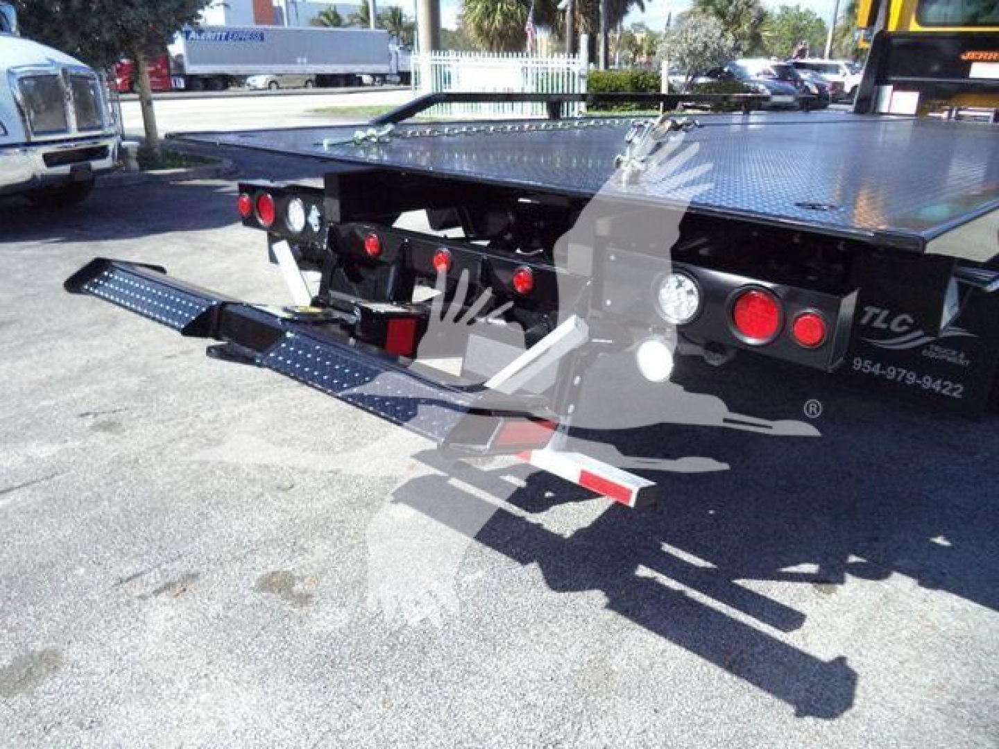 Back of a rollback truck flatbed with extendable steps and taillights visible.