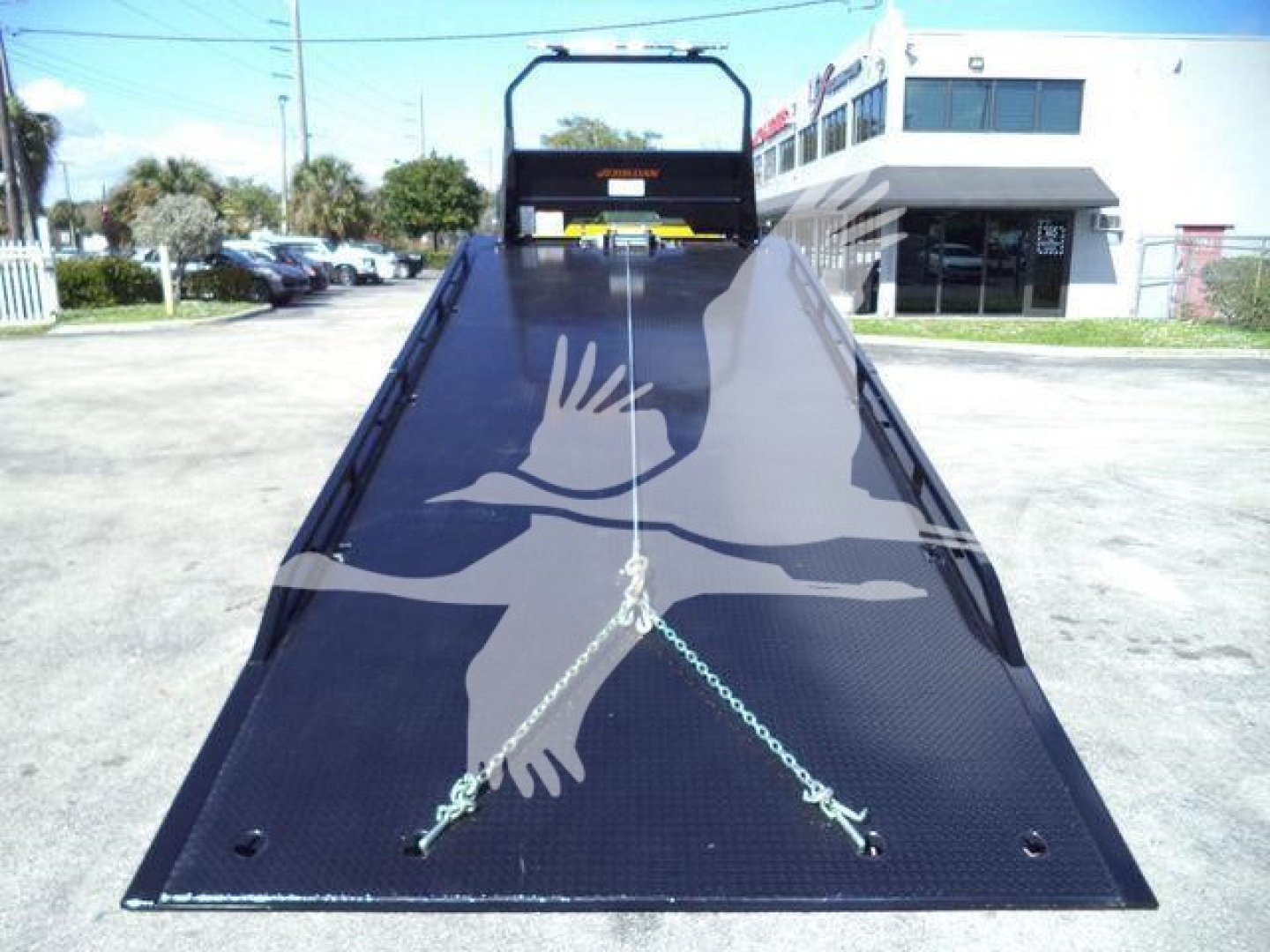 Truck bed on a 2019 International Durastar 4300 rollback showing a long flatbed with two chains secured and a manila handle at the cab.
