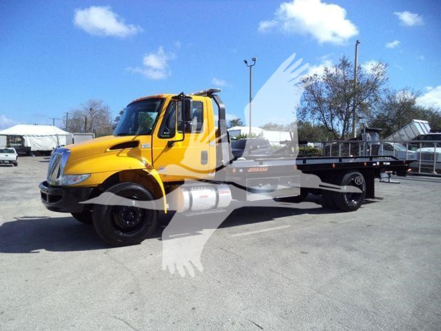 2019 International Durastar 4300 rollback truck in yellow with flatbed, side view showing cab and chassis.