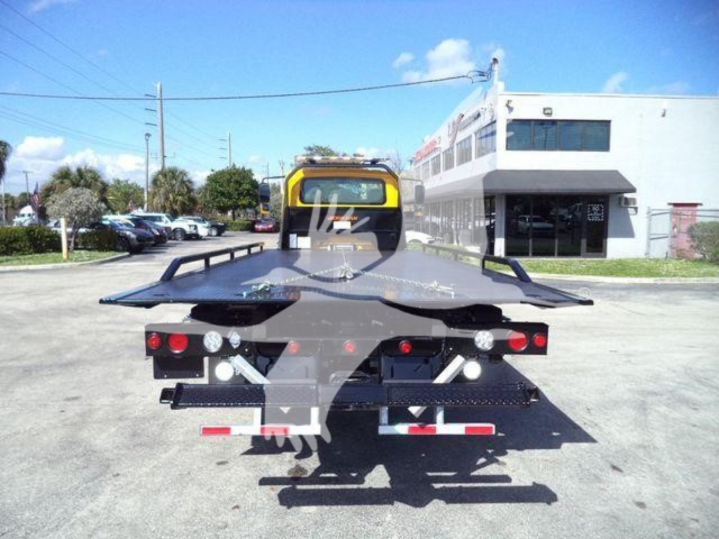 Tow truck rollback bed rear with warning lights and hydraulic ramps, International Durastar 4300 style. Visible text includes none clearly legible from distance.