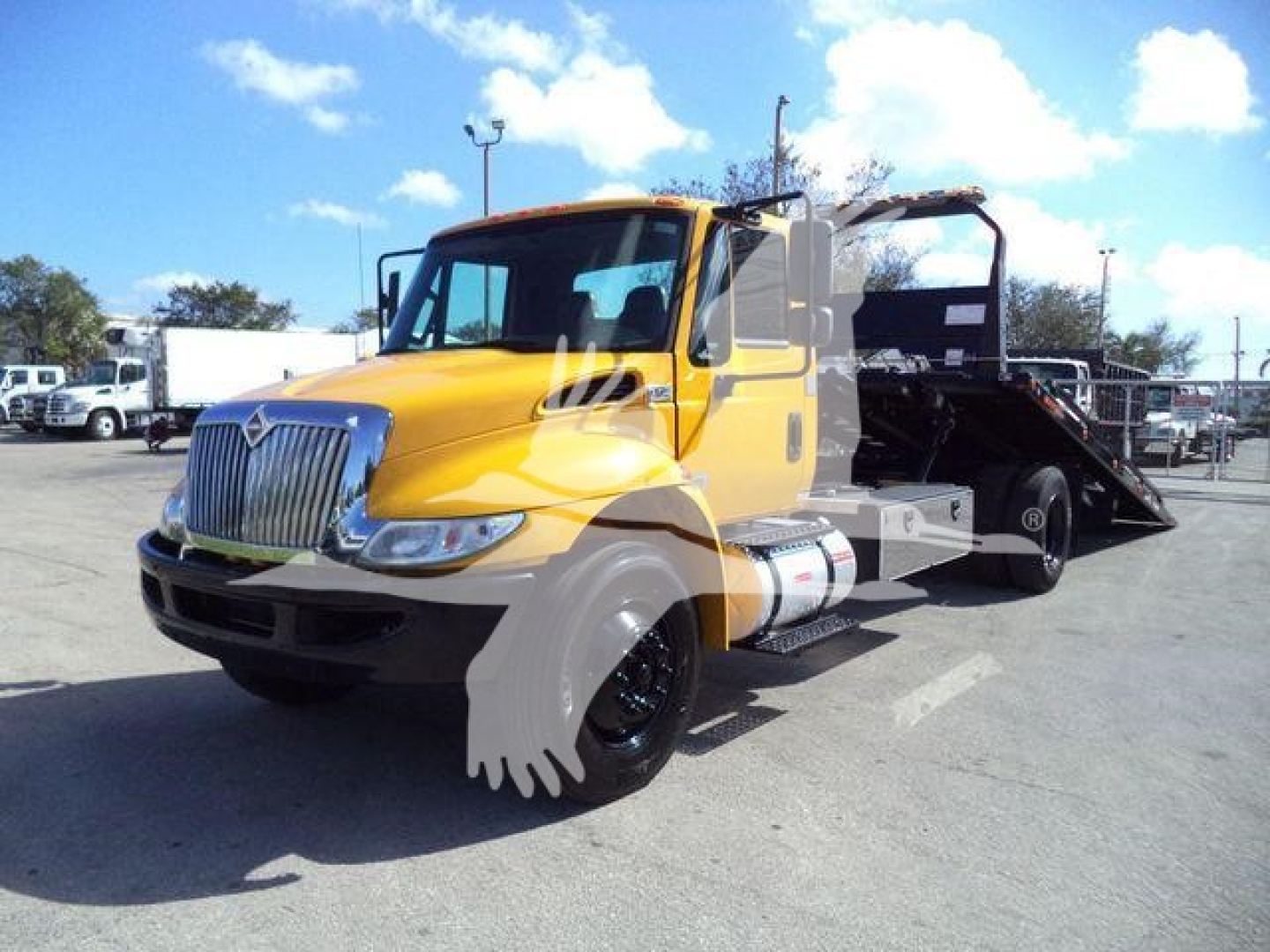 2019 International Durastar 4300 rollback truck in yellow and black, side view showing flatbed with ramp and chrome grille.