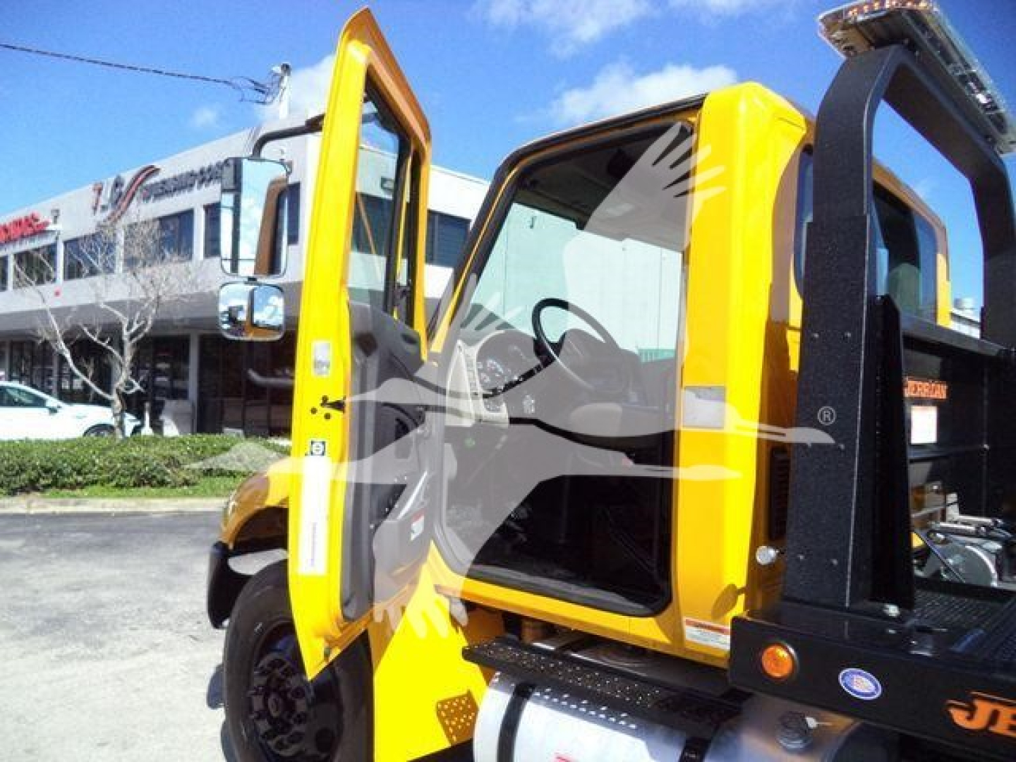 International Durastar 4300 rollback truck cab open door with yellow paint and black rollback equipment in foreground.