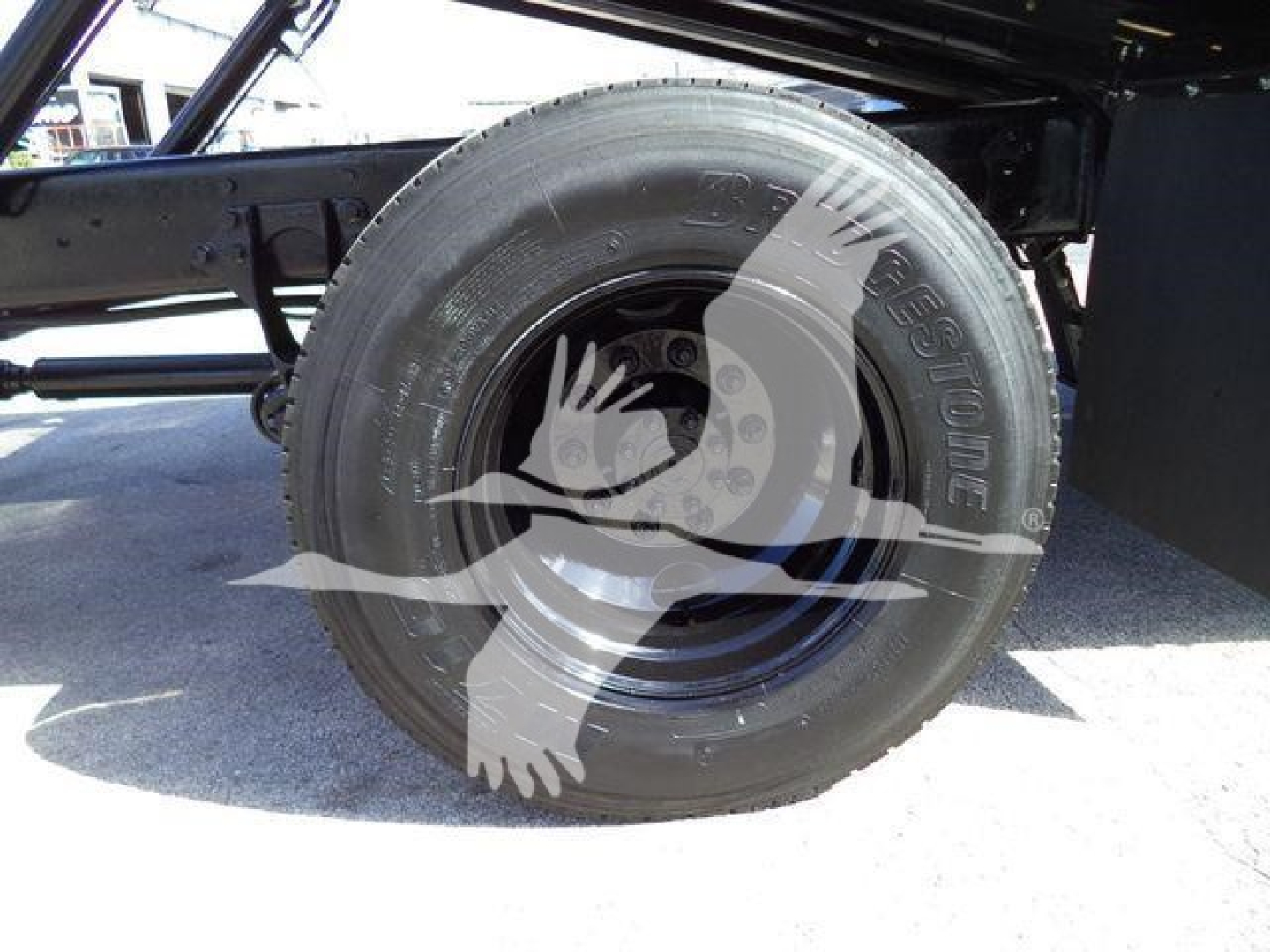 Tire close-up on wheeled truck chassis showing wheel, tire, and suspension components.