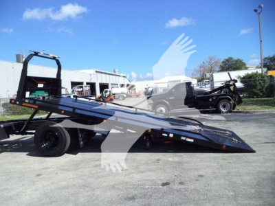 Flatbed rollback tow truck in service position showing low-profile ramp with hydraulic tilt and black chassis.