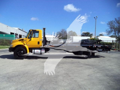 Truck showing a yellow International Durastar 4300 rollback bed with flatbed and towing equipment.