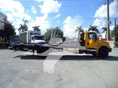 2019 International Durastar 4300 rollback truck with flatbed and crane visible, two-tone yellow cab, other trucks in background.