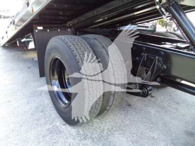 Truck rear dual tires and undercarriage of a 2019 International Durastar 4300 rollback, view of left rear wheel and suspension.