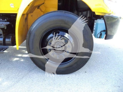 Front wheel and fender area of a yellow 2019 International Durastar 4300 rollback truck showing wheel hub and tire.