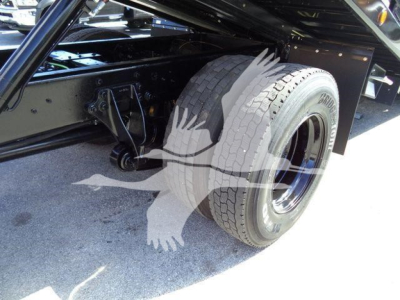 Truck rear wheel and suspension area of a 2019 International Durastar 4300 rollback, showing dual rear tires, frame, and hookups under the bed.