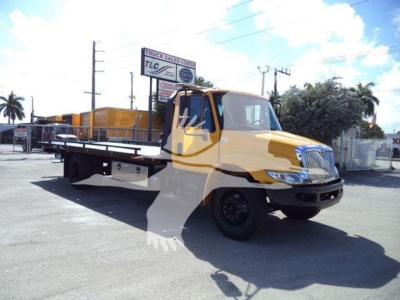 2019 International Durastar 4300 rollback truck in use showing flatbed and cab with TLC sign in background.