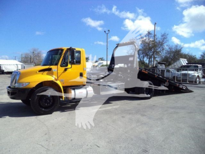 International Durastar 4300 rollback truck in yellow with a tilt-bed, side view showing cab and wheel, stock number T15548FM.