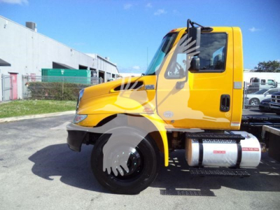 Truck cab side view of a yellow 2019 International Durastar 4300 rollback truck showing front wheel and fuel tanks.