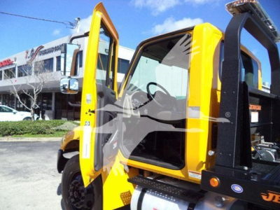 International Durastar 4300 rollback truck cab open door with yellow paint and black rollback equipment in foreground.