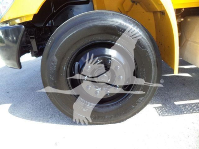 Tire close-up on a yellow International Durastar 4300 rollback truck showing a black wheel and body panel edge.