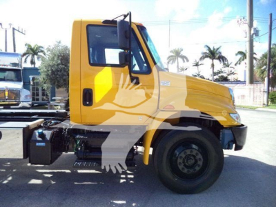 Truck cab side view of a yellow 2019 International Durastar 4300 rollback truck showing cab and front wheel