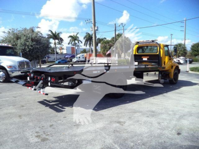 Truck tow flatbed showing International Durastar 4300 used with rollback equipment and rear wheel loader arms.