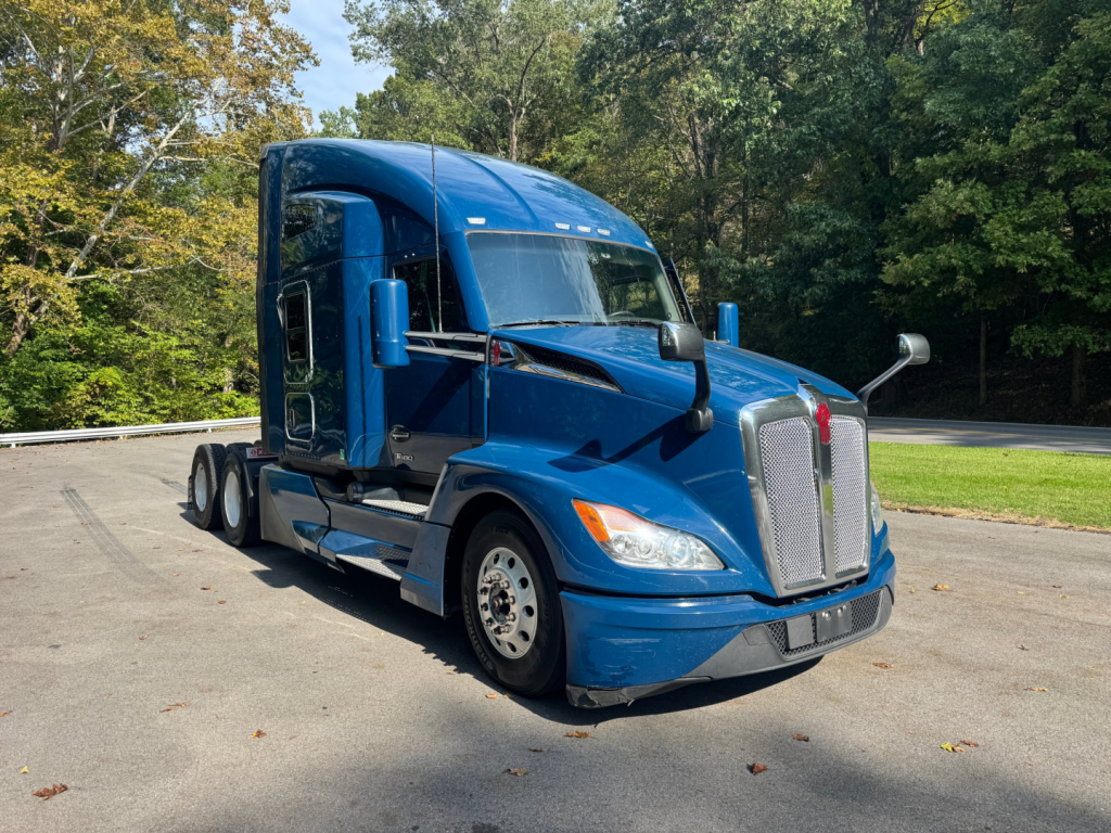 Kenworth T680 sleeper-cab truck in blue, front three-quarter view, with chrome grille and large mirrors.