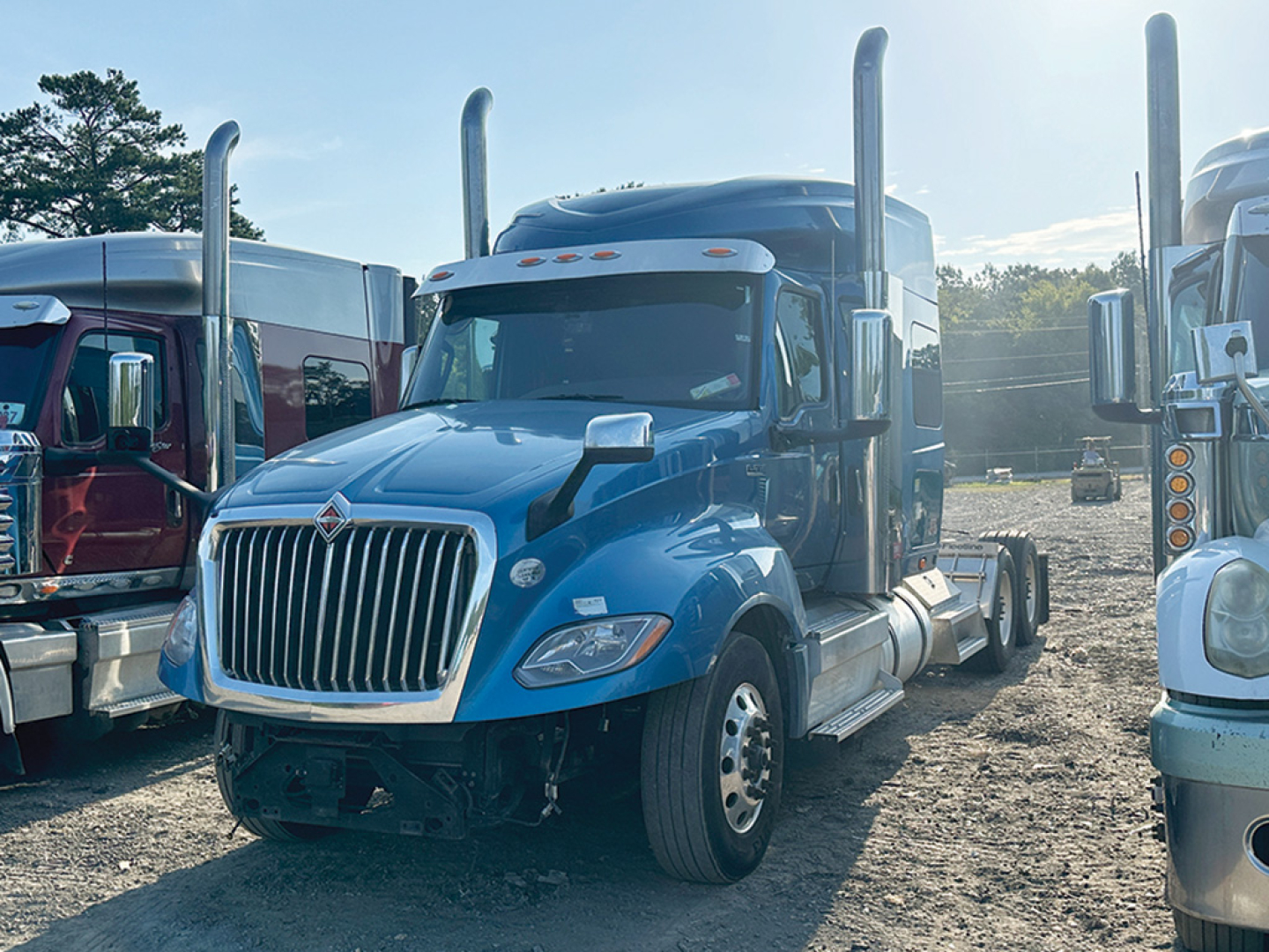 Blue 2019 International LT625 conventional daycab tractor showing front grille, headlights, tall exhaust stacks, and chrome bumper.