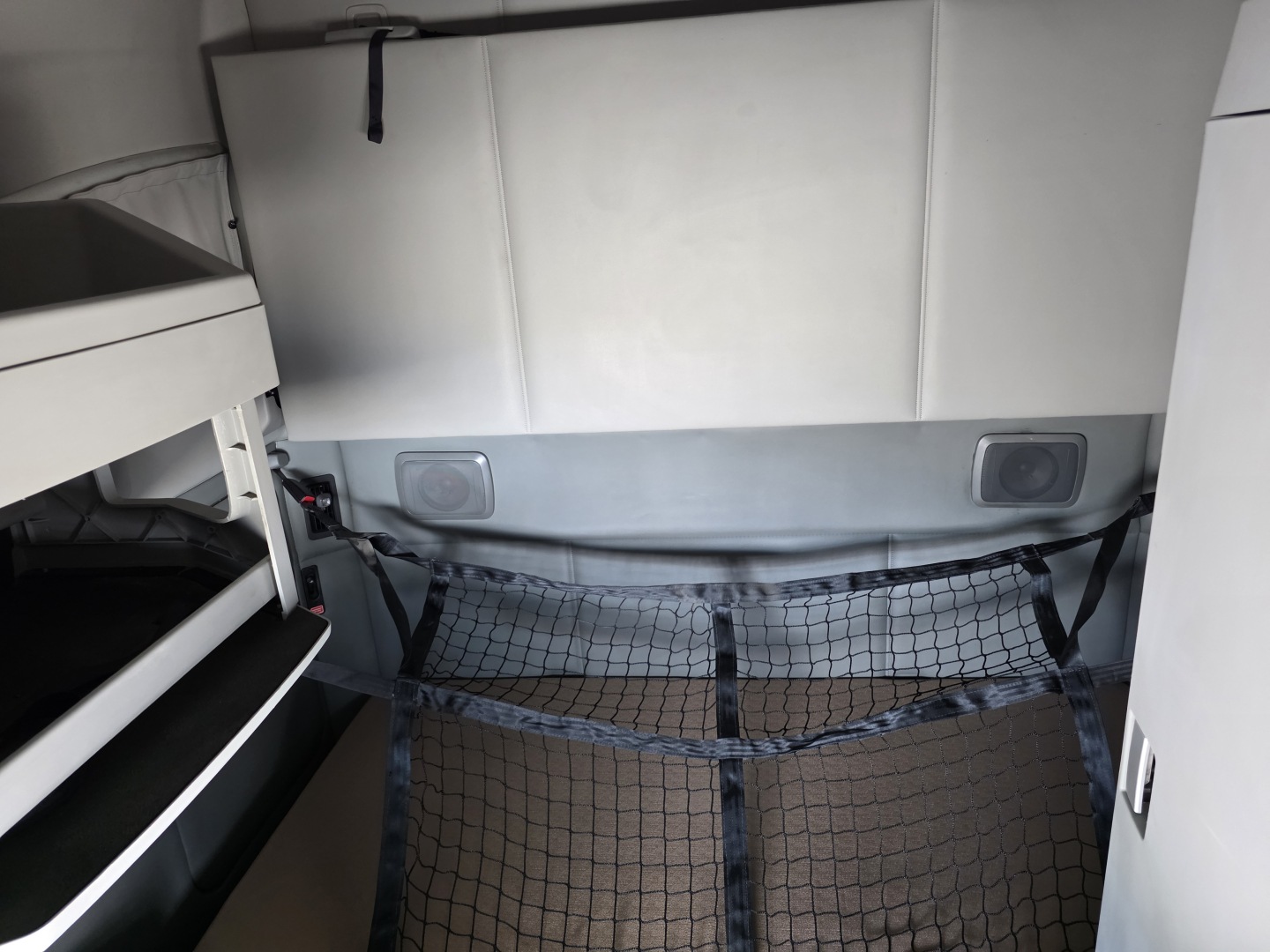 Kenworth T680 sleeper cab interior showing cargo net and storage area behind seats.