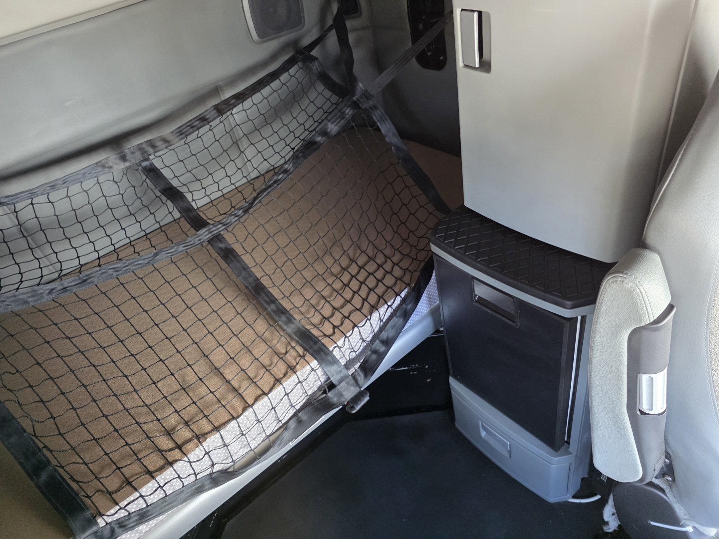 Kenworth T680 sleeper cab interior showing storage pocket and partition netting behind passenger seat.
