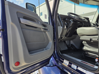 Kenworth T680 cab interior and open driver door showing steering wheel dashboard and seating.