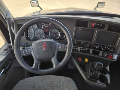 Kenworth T680 driver's cockpit showing steering wheel gauge cluster and center console with controls and gear selector.