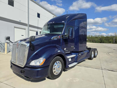 Kenworth T680 semi-truck in dark blue, front-left view, sleeper cab with chrome grille and dual rear axles.