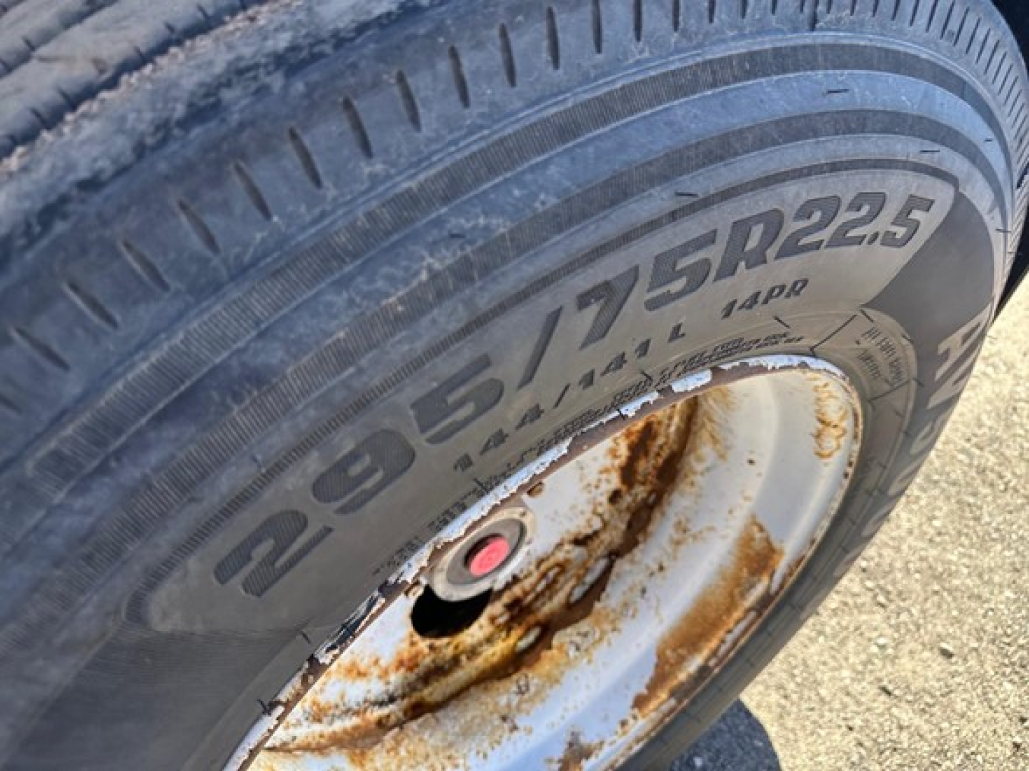 Wheel and tire showing 205/75R22.5 tire with rusted wheel hub on utility spread air combo flatbed trailer.