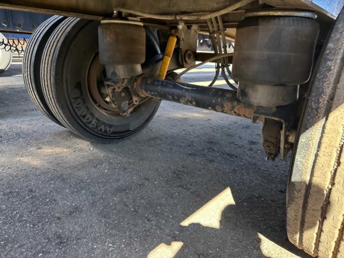 Undertruck view of a utility trailer with dual air springs and axle, showing a tire with Goodyear branding and suspension components.