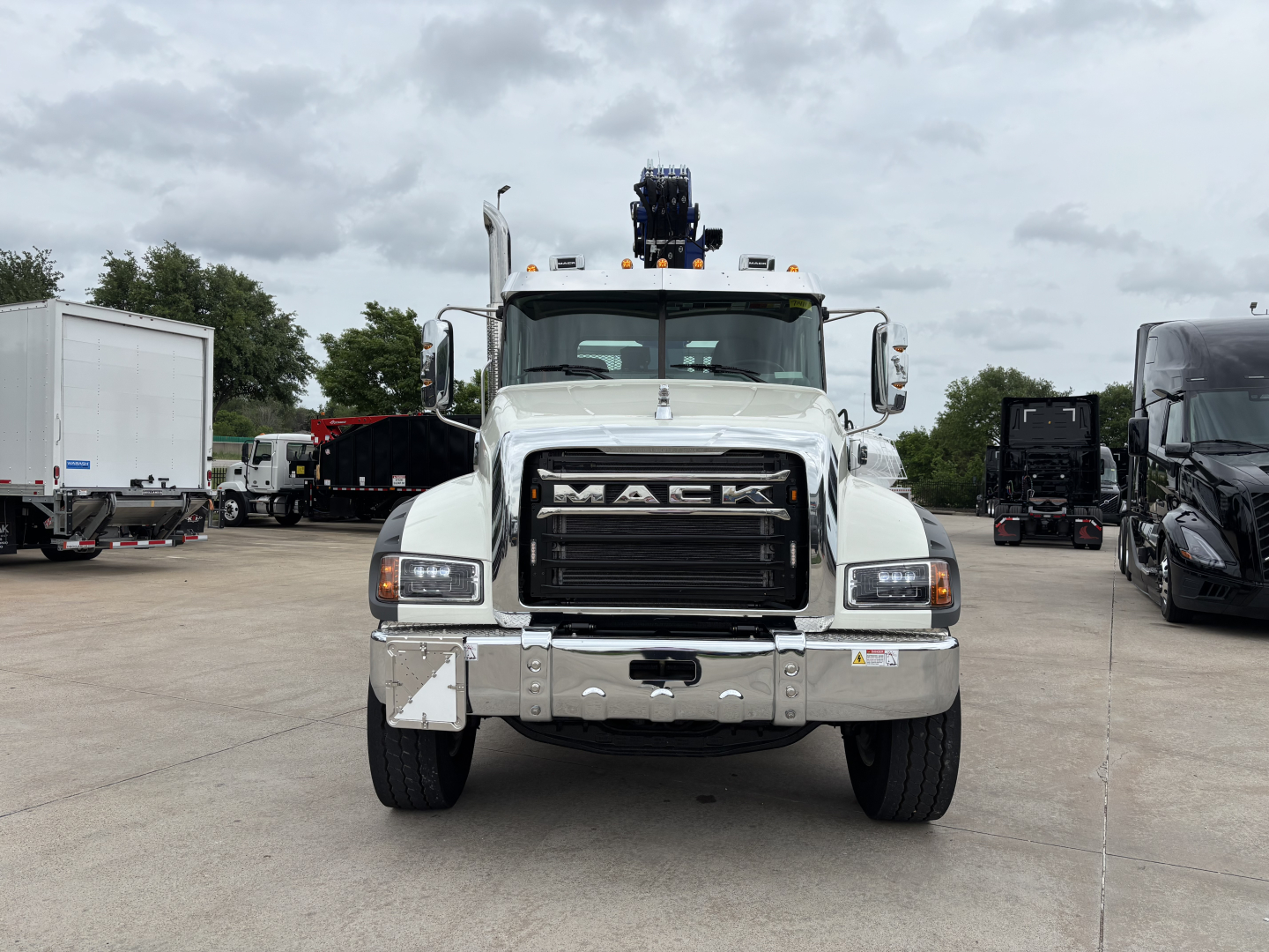 Mack GR64F crane truck front view showing Mack grille, bumper, and headlights with crane equipment on cab top.
