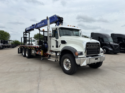 Truck cab and carose crane truck in a lot showing white Mack GR64F with blue crane arm and flatbed, VIN 1M2GR4GCXTM055964 visible on listing, stock 71411.