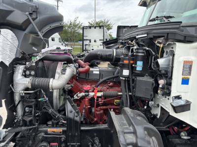 Mack GR64F crane truck engine bay showing red turbocharger, hoses, and wiring harnesses with ambient engine components and labels.