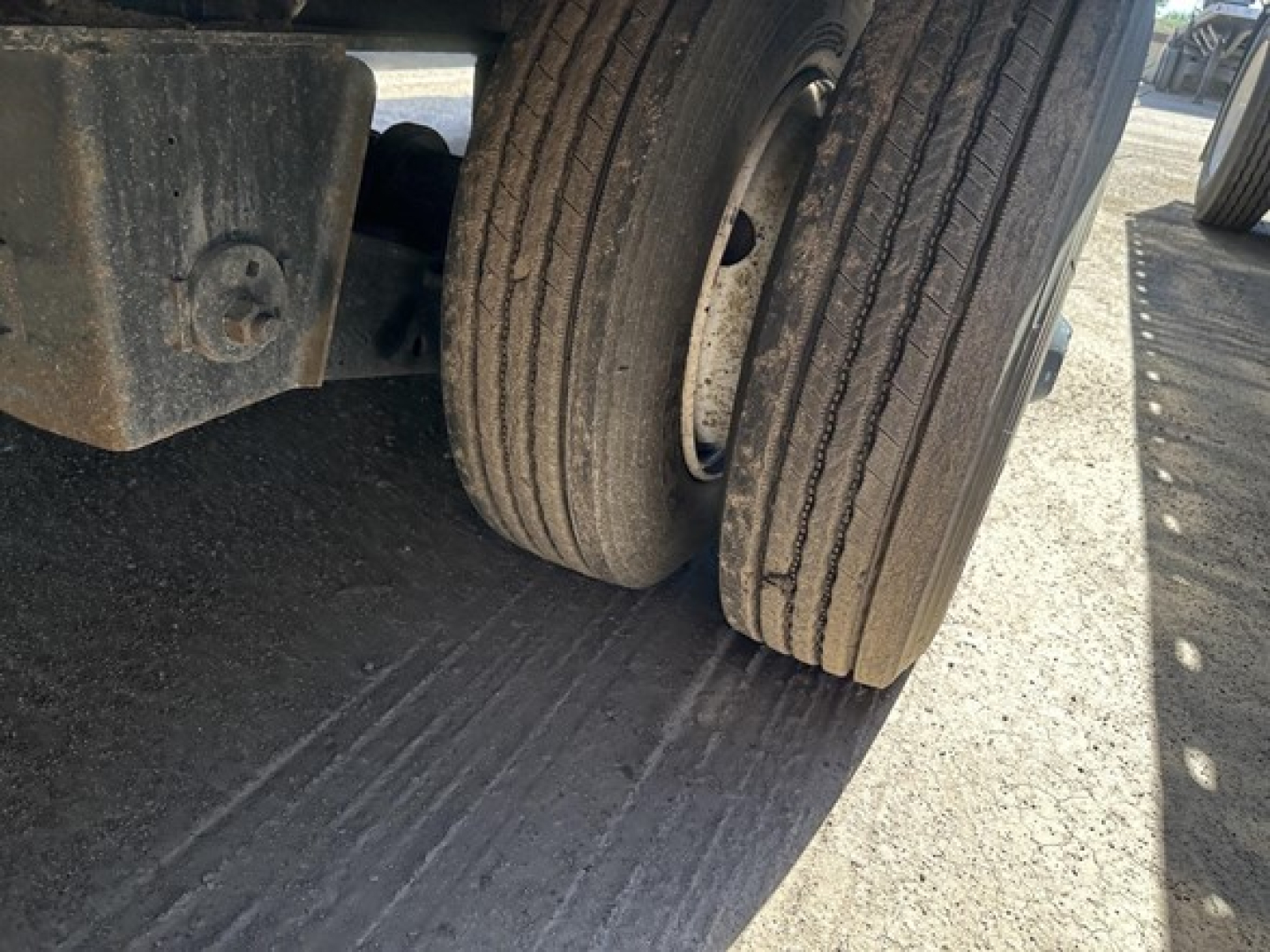 Great Dane steel spread air drop deck trailer showing dual rear tires and undercarriage with wear marks on the ground surface.