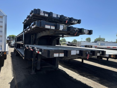 Great Dane steel spread air drop deck trailer showing stacked components and deck frame with labels and warning stickers.
