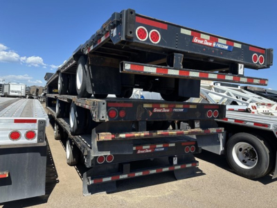Great Dane steel spread air drop deck trailer stacked with three trailers showing rear lighting and branding.