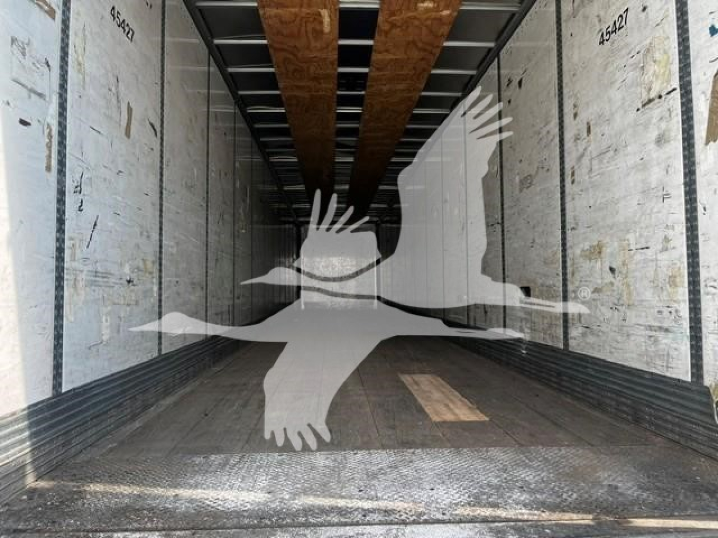 Trailer interior showing empty cargo space with wooden floor boards and side panels, watermark silhouette overlay across the image.