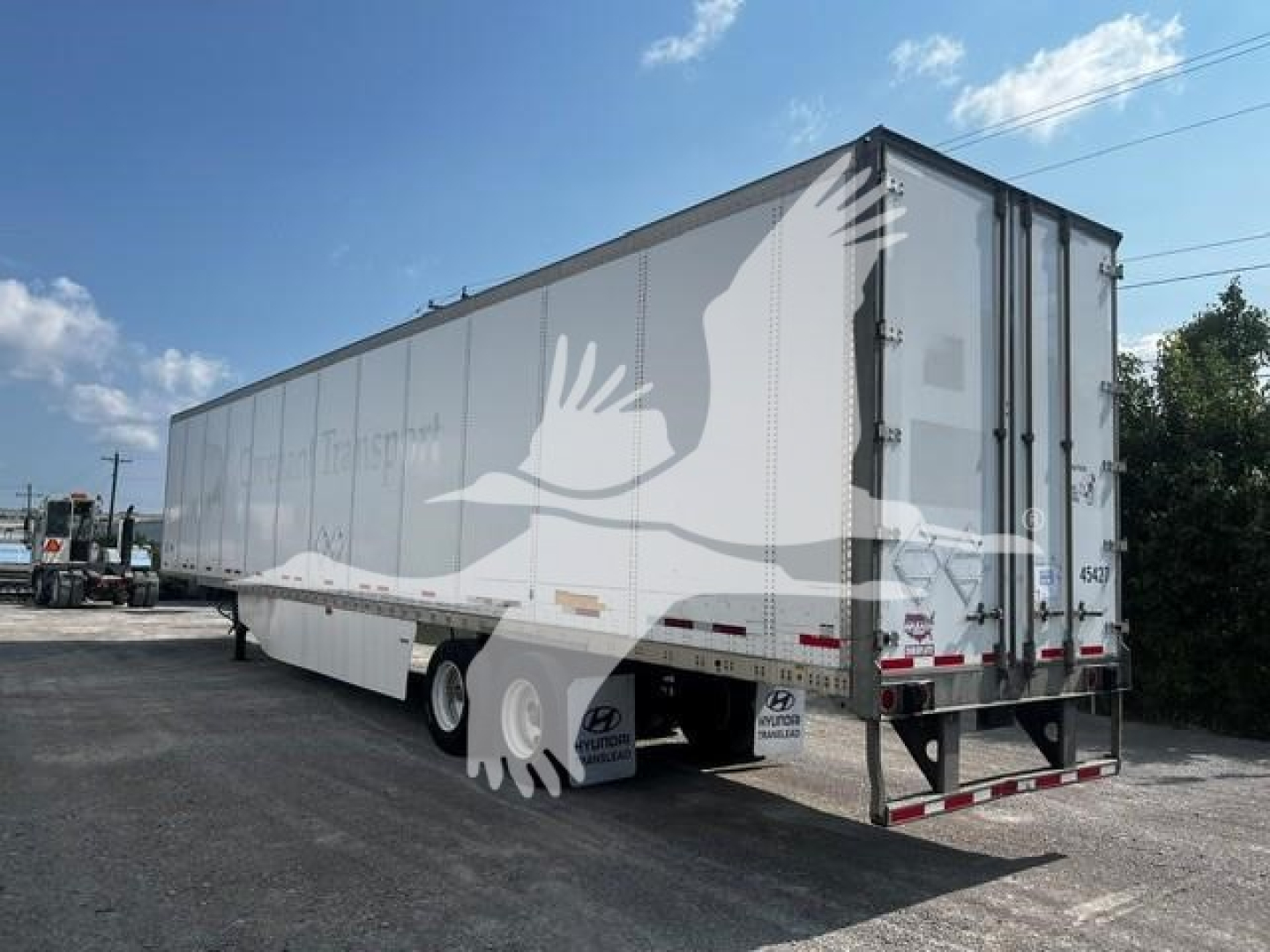 Trailer side and rear showing a white Wabash trailer with rear doors, tag lines, and reflective markers. Visible text on tires area and rear bumper unreadable.