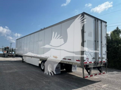Trailer side and rear showing a white Wabash trailer with rear doors, tag lines, and reflective markers. Visible text on tires area and rear bumper unreadable.