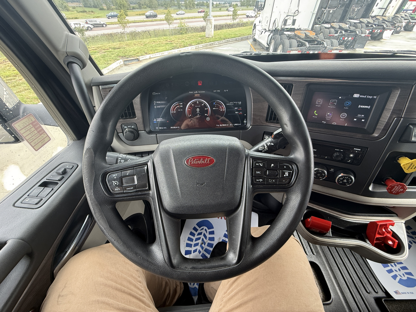 Peterbilt 579 truck interior showing steering wheel, digital instrument cluster, and touchscreen display from driver seat view.
