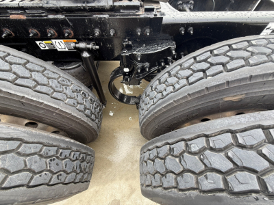 Truck chassis area showing dual rear axles with tires, undercarriage components and suspension in view.
