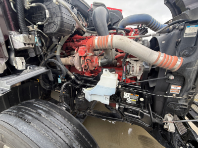 Peterbilt 579 engine bay showing turbo hoses, engine block, and coolant reservoir with orange intake hose.