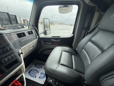 Peterbilt 579 truck cab interior showing driver seat and dashboard with gray upholstery and steering area.