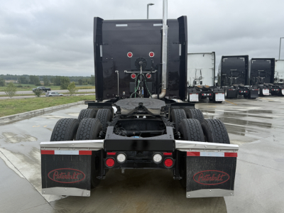 Peterbilt 579 tractor rear view showing chassis and dual rear axles, mud flaps with Peterbilt logos, and connection area for trailer.