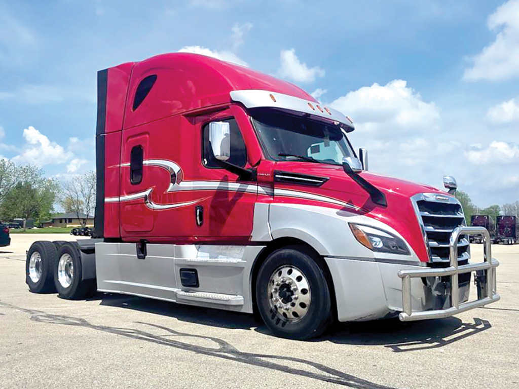 Conventional sleeper truck in red and white showing Freightliner Cascadia 126 exterior with chrome bumper guard and dual rear axles.
