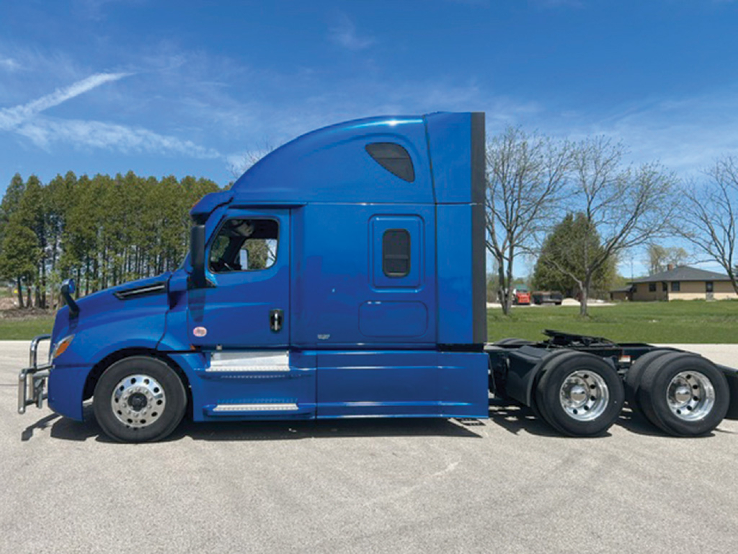 Tractor-trailer truck side view showing blue Freightliner Cascadia126 sleeper with cab, wheels, and chassis.