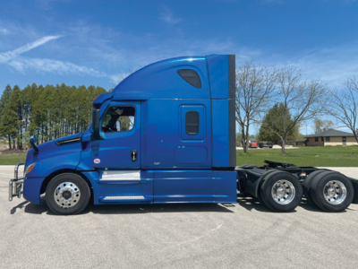 Tractor-trailer truck side view showing blue Freightliner Cascadia126 sleeper with cab, wheels, and chassis.