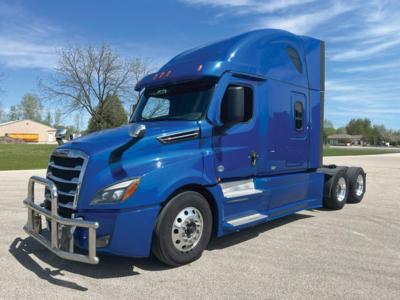 Blue Freightliner Cascadia126 sleeper cab truck with chrome front bumper guard and black side mirrors, front grille, and dual rear axles; no visible text other than reflections.