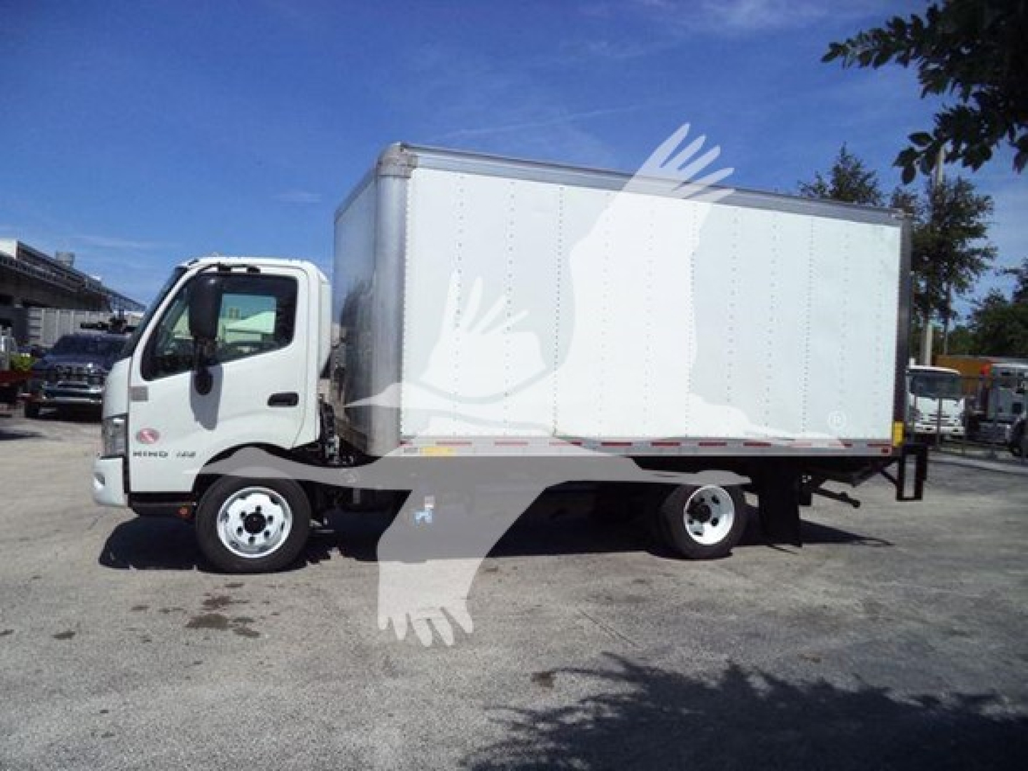 Box truck side view showing cab and cargo box. Visible text includes Hino badge on door and 'HINO' emblem. No other legible text.