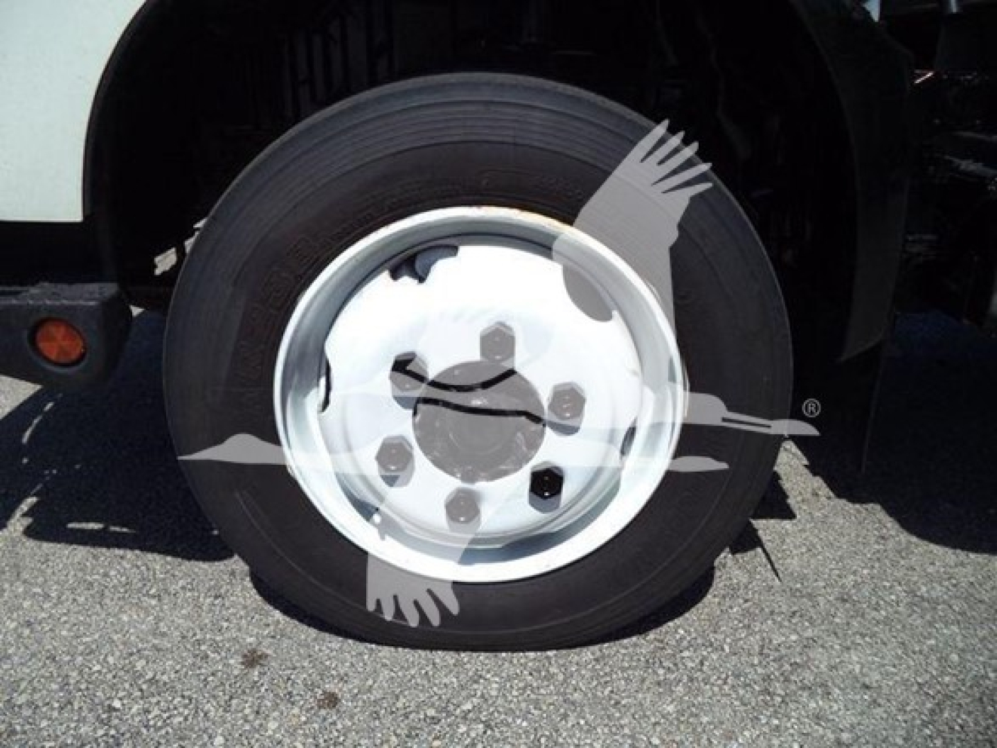 Wheel and tire assembly on front axle of a 2020 Hino truck showing wheel hub and tire with white rim.