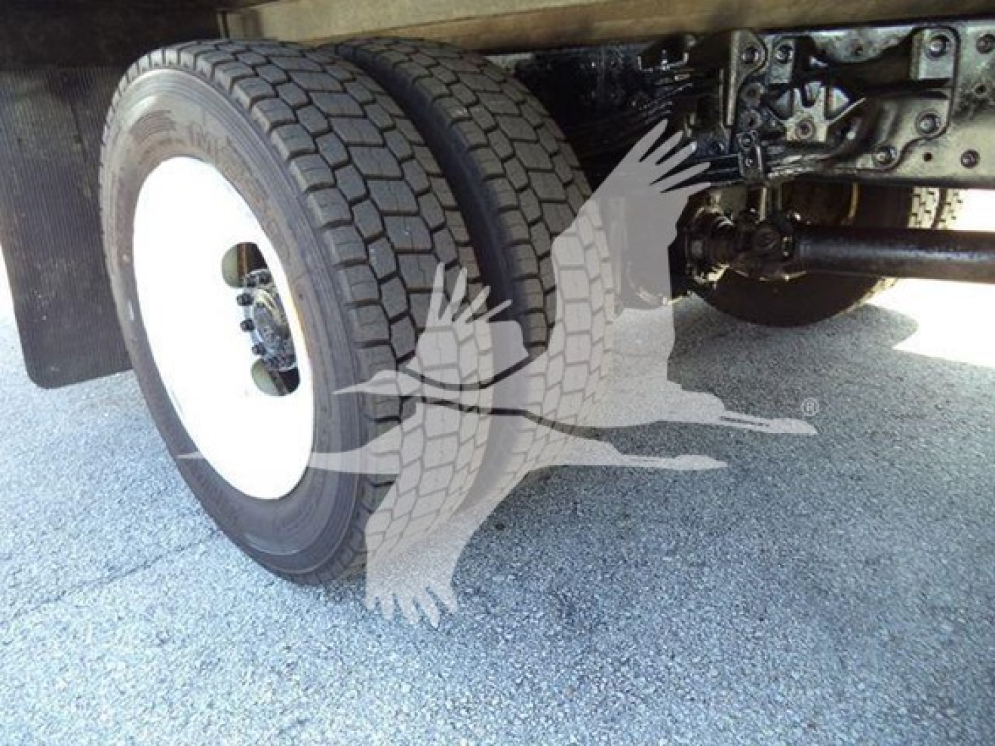 Truck undercarriage showing front dual wheels and suspension components.